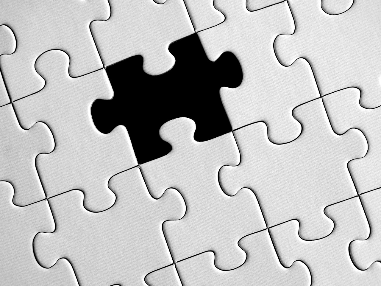 A nearly complete white puzzle with one central piece missing